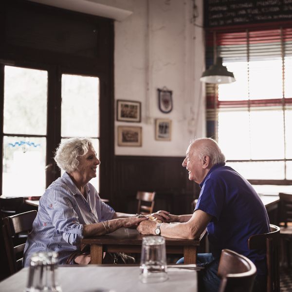 Zwei Menschen sitzen im Café, halten gegenseitig die Hände und schauen sich tief in die Augen. Es zeigt wie wichtig Cafés für Dates in Dresden sind. 