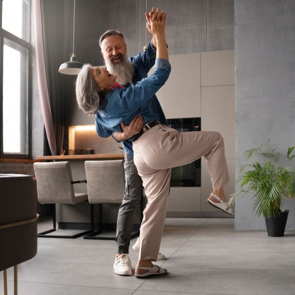 Ein fröhliches Paar tanzt gemeinsam in einer Wohnung. Es steht für Lebensfreude, Leichtigkeit und neue Begegnungen beim Dating über 40 in Köln.