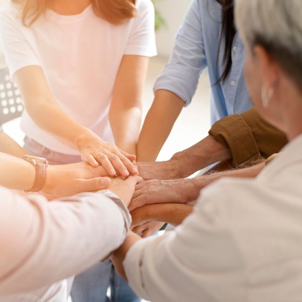 Menschen legen ihre Hände übereinander als Zeichen von Zusammenhalt und Engagement. Ein Symbol für Gemeinschaft, neue Kontakte und gemeinsame Aktivitäten beim Dating über 40 in Köln.