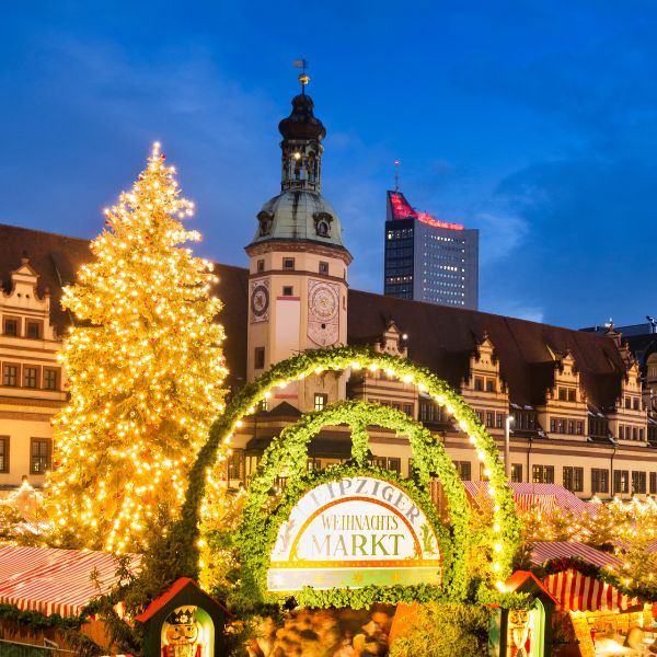 Festlich beleuchteter Leipziger Weihnachtsmarkt mit großem Weihnachtsbaum, historischen Gebäuden im Hintergrund und stimmungsvoller Abendkulisse. Eine Date-Möglichkeit auf Weihnachtsmärkten für Singles.