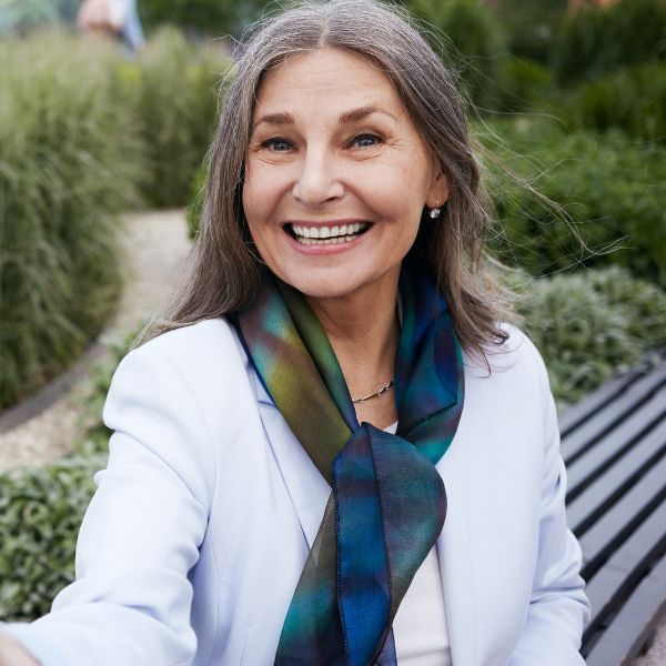 Frau lächelt in die Kamera. Es ist ein Profilbild für Partnersuche beim Online-Dating.