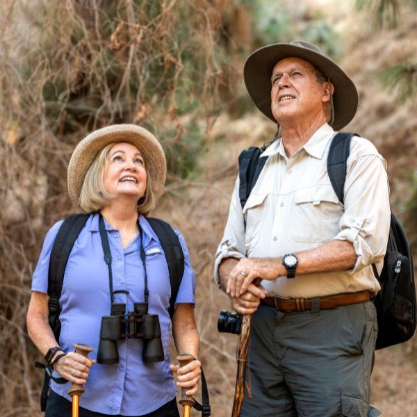 Ein älteres Paar beim Dating in Hamburg über 40 unternimmt gemeinsam eine Wanderung, trägt Rucksäcke und Sonnenhüte und genießt die Natur mit Freude und Neugier.